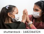 Mother and daughter wear medical masks and clasp hands in hopes that everything will pass. Coronavirus infection concept Covid-19.