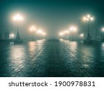 The main alley of a night winter park in a fog. Footpath in a fabulous winter city park at night in fog with benches and latterns. Beautiful foggy evening in the Mariinsky Park. Kyiv, Ukraine.
