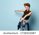 Small photo of Funny boy in stylish cap jumping in place looking down under feet with roguish smile. Childhood, sly kid, troublemaker. Three quarter length portrait isolated on blue background. Copy space