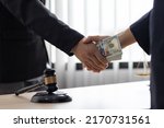 Small photo of Business people shaking hands and bribe to an attorney to help a lawyer win a court case. The concept of bribing lawyers and paying lawsuits.