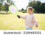 Active preschool girl playing badminton in outdoor court in summer. Kid with racket.