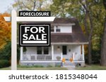 Small photo of Black Foreclosure Home For Sale Real Estate Sign in front of an quaint countryside home.