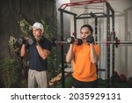 A couple does a set of dumbbell shoulder thrusters at a home gym. Deltoid workout.