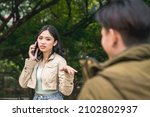 Small photo of An annoyed young lady rebuffs a bothersome man while talking on her phone. An inappropriate approach