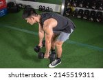 Small photo of A fit asian man does Romanian dumbbell deadlifts or bent over rows. Weight and resistance training at the gym.