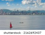 Small photo of The Cebu City skyline and the abridge as seen from the Cebu Straight. A buoy and a small fishing boat in front.