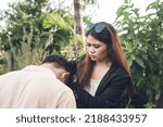 Small photo of A livid young woman pulls her boyfriend's hair out of rage and intense jealousy. A possessive and physically abusive girlfriend. Outdoor scene.