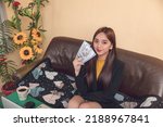 Small photo of Young adult female with long brown hair flashing some cash. High wage earner with a lucrative job. She is wearing a yellow and black top.
