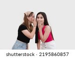Small photo of A woman shares some juicy secret gossip from the grapevine to her friend, who is gasping from the controversial and intriguing hearsay. Isolated on a white backdrop.