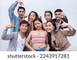 A group of seven happy and young people in their late teens to early 20s pointing to their friend in the middle. Presentation and advertising concept. Isolated on a white backdrop.