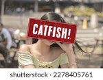Small photo of A catfish alert sign or someone pretending to be an attractive person. A fake profile using a stolen photo. A false identity used to pursue deceptive online romance. Catfishing detection concept.