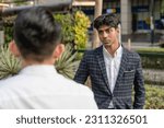 Small photo of A hotheaded young indian man stares down his workmate while outside the office. Animosity in the workplace.