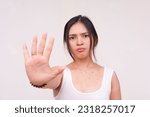 Small photo of An infuriated and serious young Asian woman doing a stop gesture with one hand. Isolated on a white background.