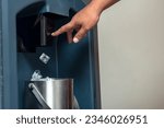 Small photo of A man presses down on a lever to drop ice cubes from a dispenser into a small stainless bucket. Using a commercial grade hotel ice maker.