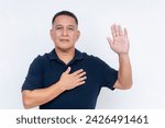 Small photo of Serious middle aged man pledging allegiance with hand raised and other on heart, symbolizing a solemn oath or pledge.