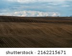 Rows of soil before planting. Drawing of furrows on a plowed field prepared for spring sowing of agricultural crops. View of the land prepared for planting and growing crops.