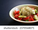Small photo of Vegetable salad with the addition of alfalfa sprouts on a gray background. Salad of cucumbers, tomatoes and alfalfa sprouts. Healthy Eating.