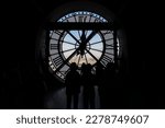 Unrecognizable people have a view of the city of Paris through a clock with a window