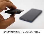 Battery Swollen in man's hand, white background and holding a smartphone.