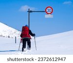 Small photo of Hiker walking toward a road sign half buried under deep snow (Niseko, Hokkaido, Japan)
