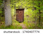 beautiful wooden professionally repaired outhouse in a green forest serves as a toilet in nature