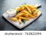 Homemade Baked Potato Fries with Mayonnaise and rosemary on white wooden board