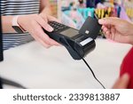 Small photo of Close-up hands of salesperson in a store with POS terminal while a customer swipes a black moockup credit card, making contactless payments. Paying goods using online internet banking, NFC technology