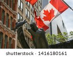 Small photo of Ottawa, Canada - May 24 2009 - A close up image of a statue named named Territorial Prerogative of a grizzly bear eating a fish with a Canadian flag in the background. It was sculpted by Bruce Garner.