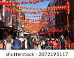 Small photo of London, UK - April 22 2021 - Tourists and locals walking and dining outside on Gerrard St in London's Chinatown, under strings of red lantern bunting