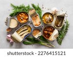 Small photo of Different open tin cans with canned fish among spices and herbs, canned salmon and mackerel, sprat and sardine, tuna and herring and fish pate, top view