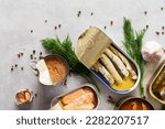 Small photo of Different open tin cans with canned fish among spices and herbs, canned salmon and mackerel, sprat and sardine, tuna and herring and fish pate, top view