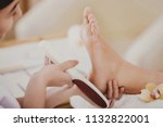 Young Beautiful Woman Does Pedicure in Spa Salon. Scrape Dead Skin by Means of Special Grater. Peeling of Heels. Process of Professional Pedicures. Concept of Beauty Care and Health.
