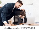 Father and son spend time together. Dad and son in the same clothes. Father teaches his son the basics of business. The son is sitting at the laptop, his father is standing next to him.