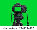 Dslr camera with empty screen on the tripod, isolated on green background. Green screen camera.