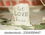 Small photo of Canvass bag that reads "let Love Brew" wedding center piece filled with cofee grinds on dinner table
