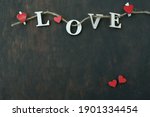  Concept for Valentine's Day. Word love on twine with clothespins and red hearts on wooden background                              