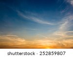 Evening sky scene with golden light from the setting sun and blue-tinting filled with white cloud streaks