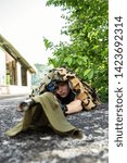 Small photo of Young sniper soldier special force covered with camouflage net aiming to the enemy waiting for the target to shoot airsoft war game