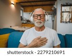 Small photo of One man senior caucasian male eyes closed for guided training yoga or meditation while sitting at home with headphones self-care practice real people well-being inner peace and balance concept