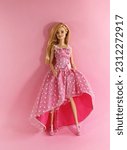 Small photo of Randburg, South Africa 05-29-2023: Beautiful Barbie in an elegant dress posed against a neutral pink background. Shallow depth of field.