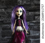 Small photo of Randburg, South Africa: 09-25-2023: Pretty ghostly doll posed isolated against a dark stone background. Monster High Spectra Vondergeist. Halloween. Shallow depth of field.