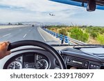 View from inside the cabin of a truck driving on a highway and a plane flying at low altitude