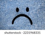 Small photo of Sad face drawn on a blue sweater as blue background. Blue Monday concept in January. Isolated depressed, joyless, annoyed, gloomy and upset mouth face. Horizontal photo with copy space.