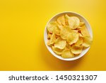 Close-up of potato chips or crisps in bowl against yellow background