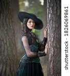 Small photo of Dark-haired aristocratic lady in a green dress in a pine forest
