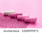 Trendy design template with nail polish glass bottles on pink and sparkling background. Manicure concept. Mockup for your design with copy space.