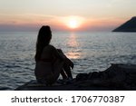 Silhouette of a young girl at the beaching watching the sunset