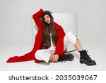 Fashionable  model in stylish  hat, red coat and boots  posing on white background in studio.  