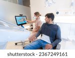 Small photo of Dentist using modern technology to explain the dental procedure to a man sitting on the clinic