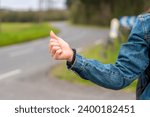Close-up photo of the hand of a woman hitchhiking in a rural road